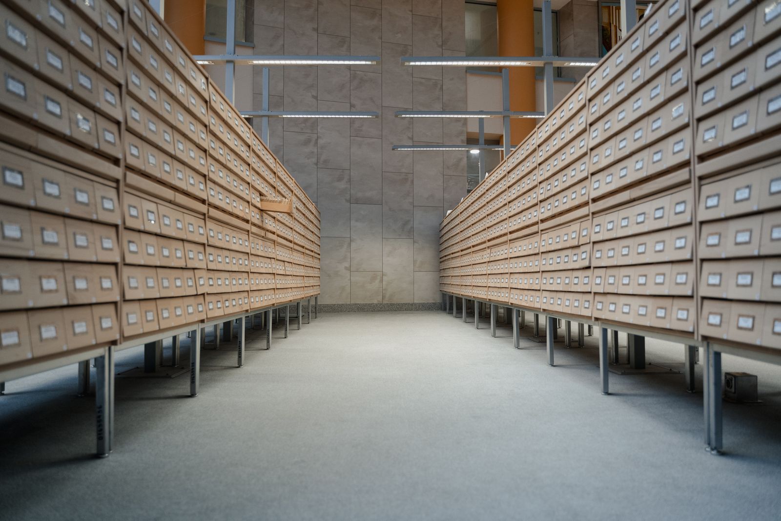 Archive room with rows of shelves holding labeled document storage drawers
